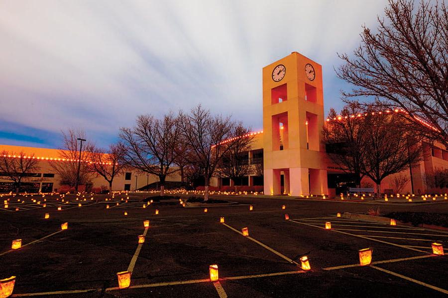 San Juan College clocktower with luminarias surrounding it.